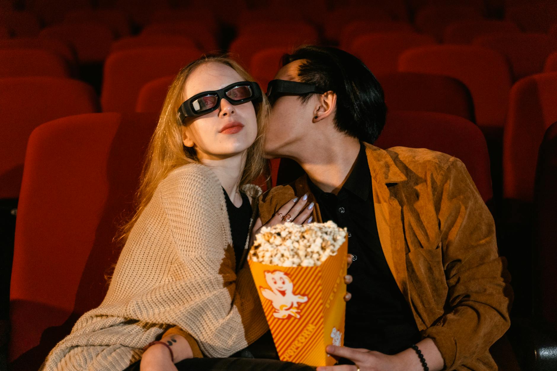 Para na taniej randce w kinie, ogląda film 3D i je popcorn
