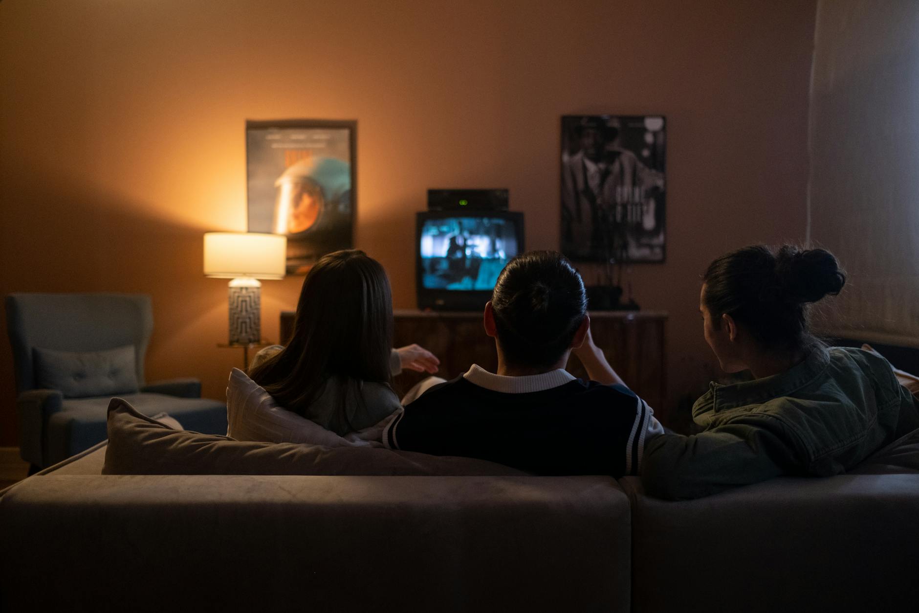 Trzy osoby na kanapie oglądają film w przytulnym salonie