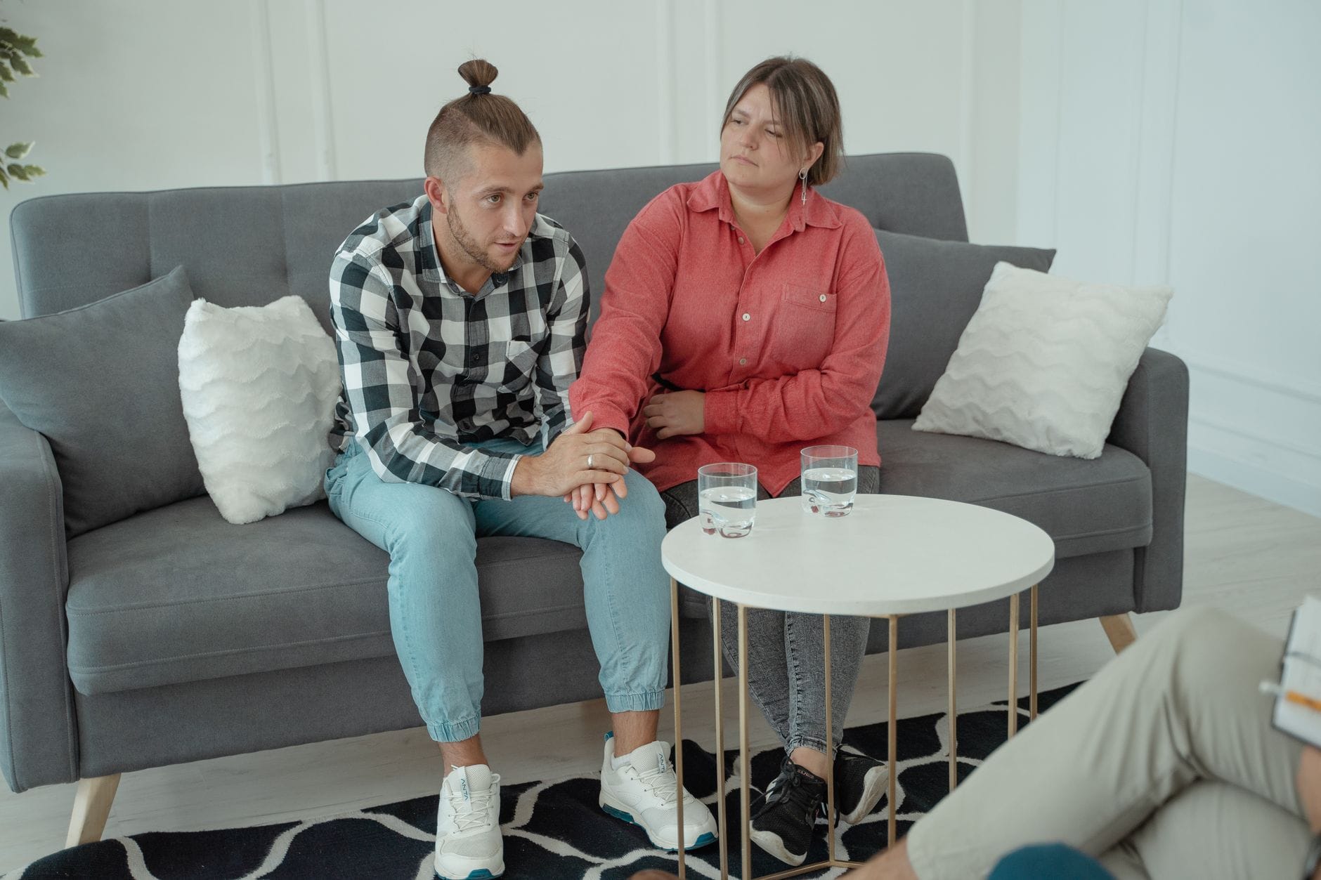 Para trzymająca się za ręce na kanapie podczas sesji terapeutycznej