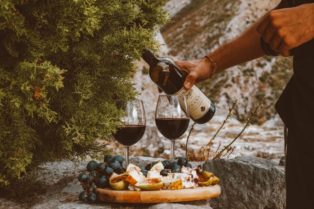Czerwone wino, sery i winogrona na kamiennym stole na świeżym powietrzu